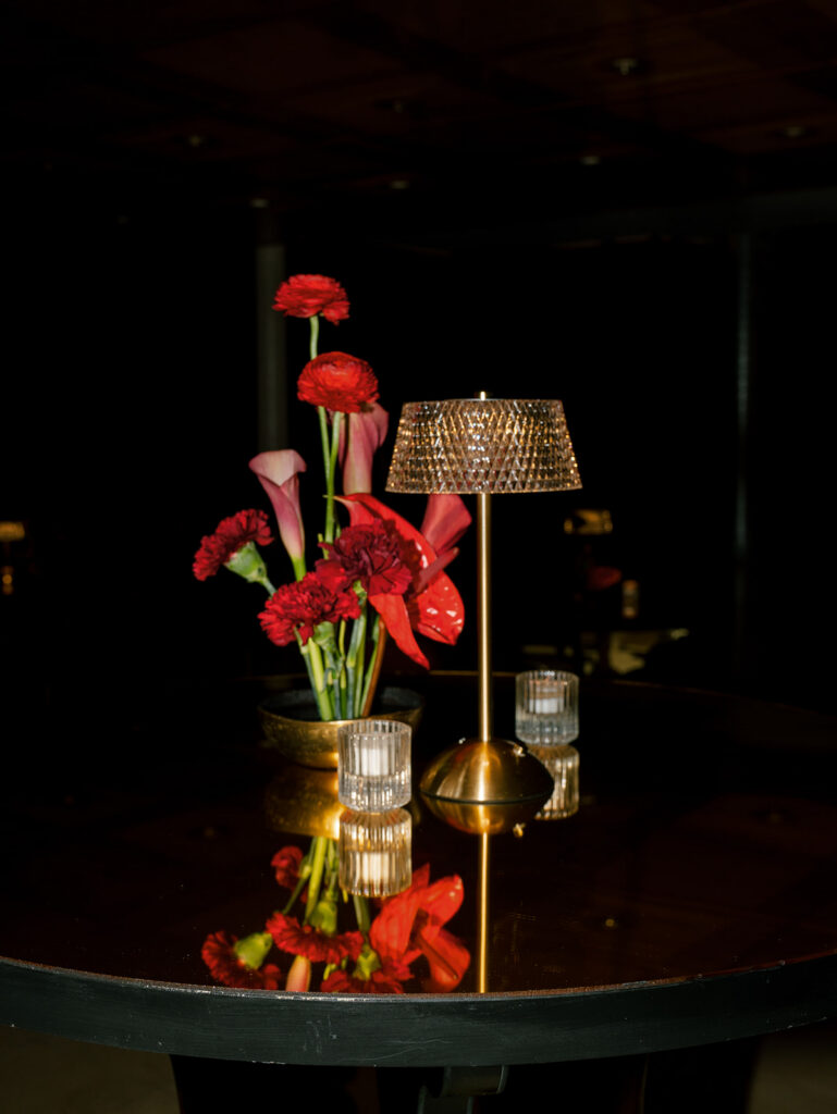 The design detail of the cocktail hour with lamps and red flower arrangements.
