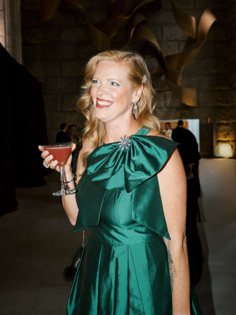 A portrait of a guest in a green dress enjoying a drink during cocktail hour.