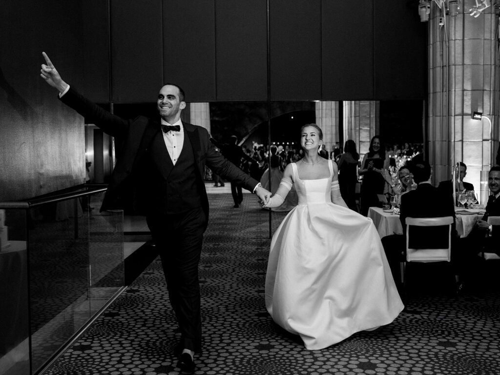 The bride and groom happily entering the room of their reception at Guastavino's.