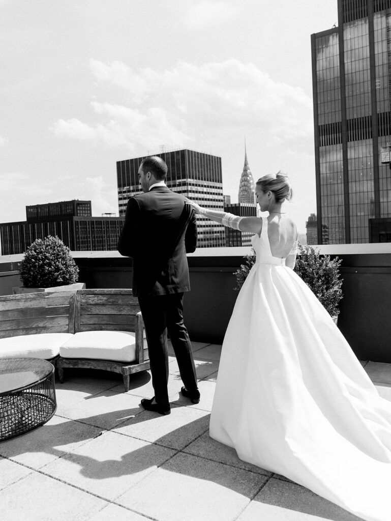 Bride tapping the groom's shoulder during their first look of the rooftop of the Lotte.