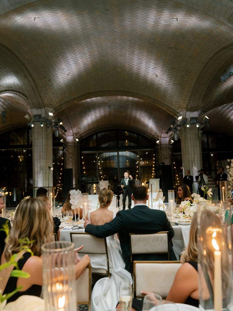 A pulled back view of speeches from behind the bride and groom.