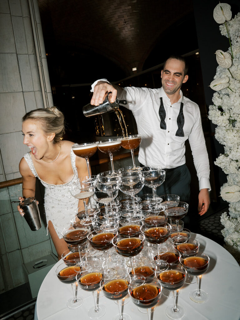 The bride and groom pouring espresso into a espresso martini tower.