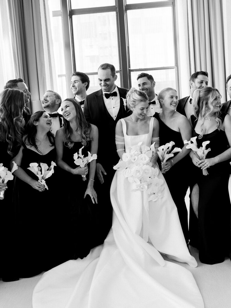 Full wedding party candid portrait with bride and groom in the middle.