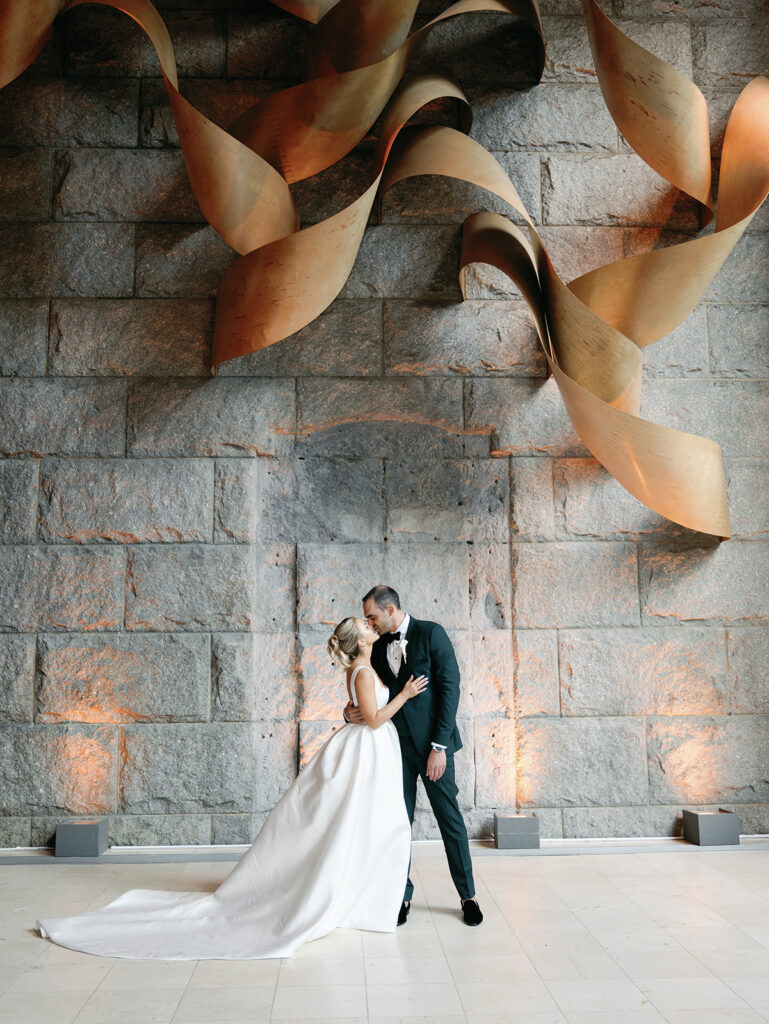 Bride and groom kissing in a portrait under the art installation at their Guastavino's wedding.