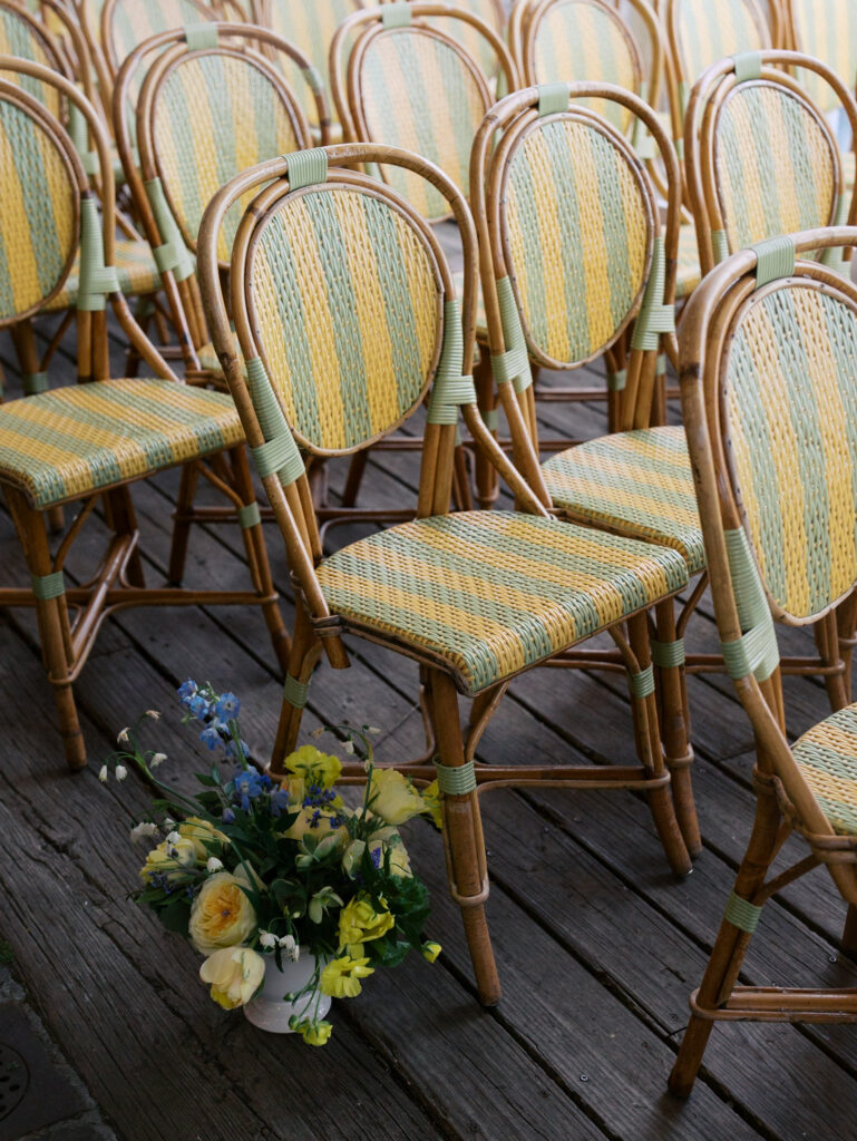 Detail photo of the iconic chairs at the river cafe during the ceremont with a floral bouquet at their feet.