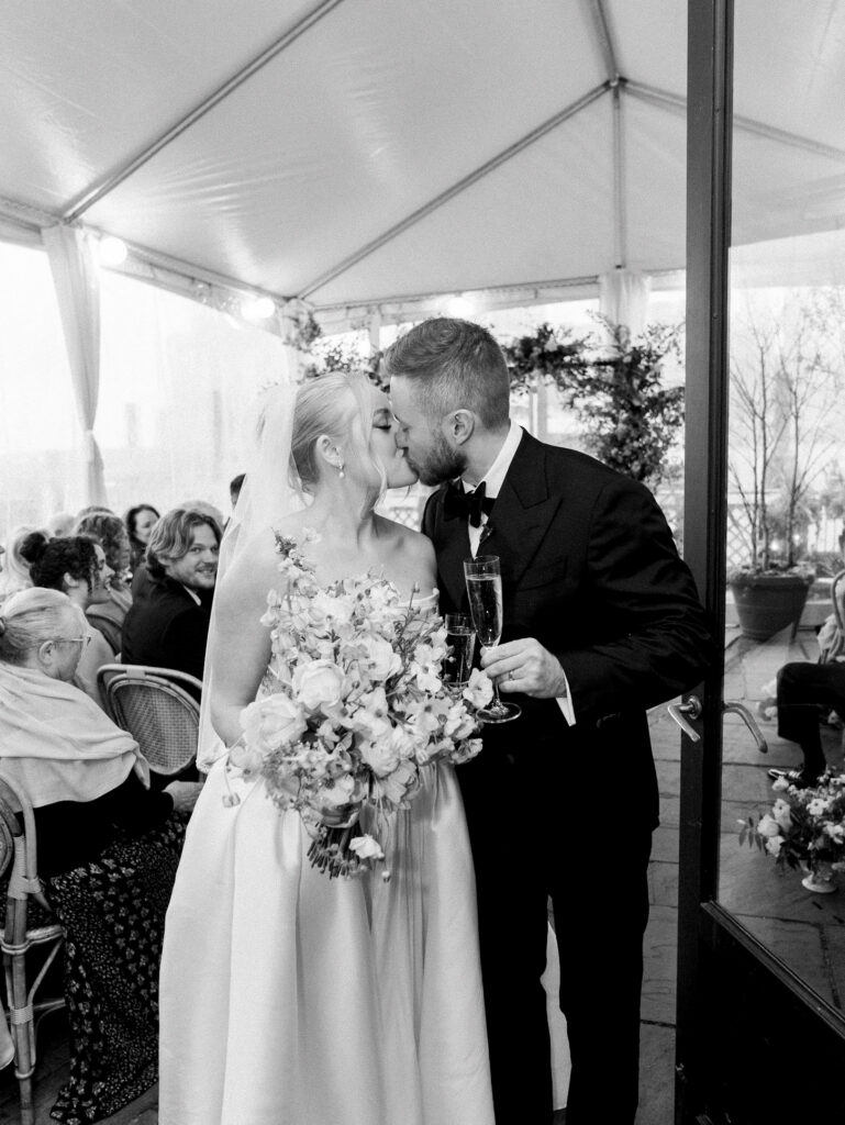 Bride and groom aisle kiss after their rainy river cafe wedding.