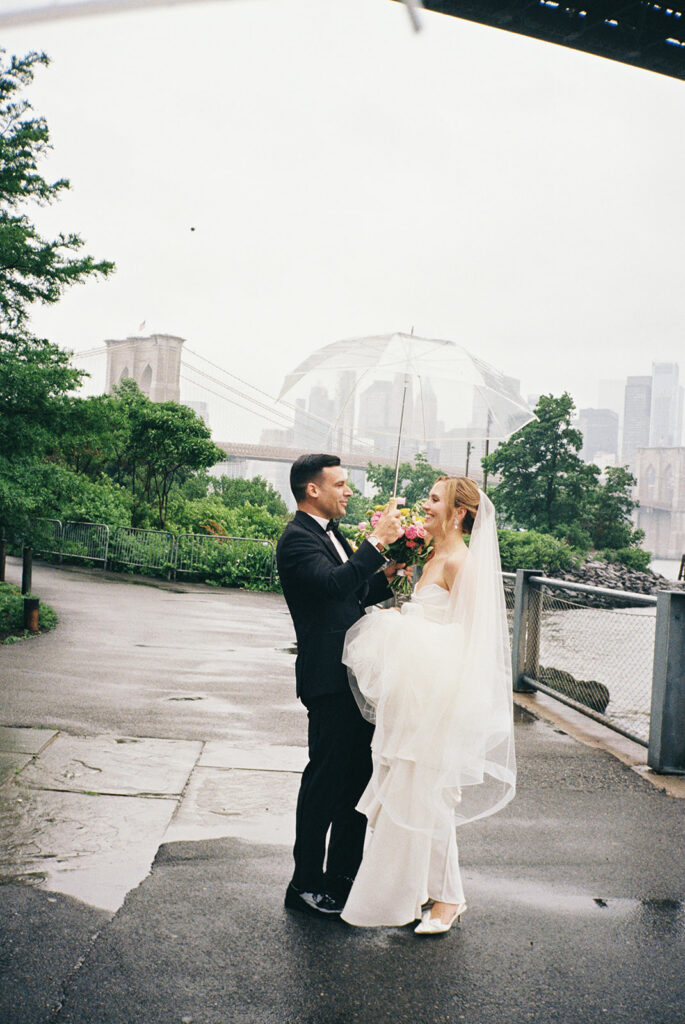 A bride and groom sharing a candid moment under the bride in Brooklyn. the groom is holding an umbrella above the bride's head.