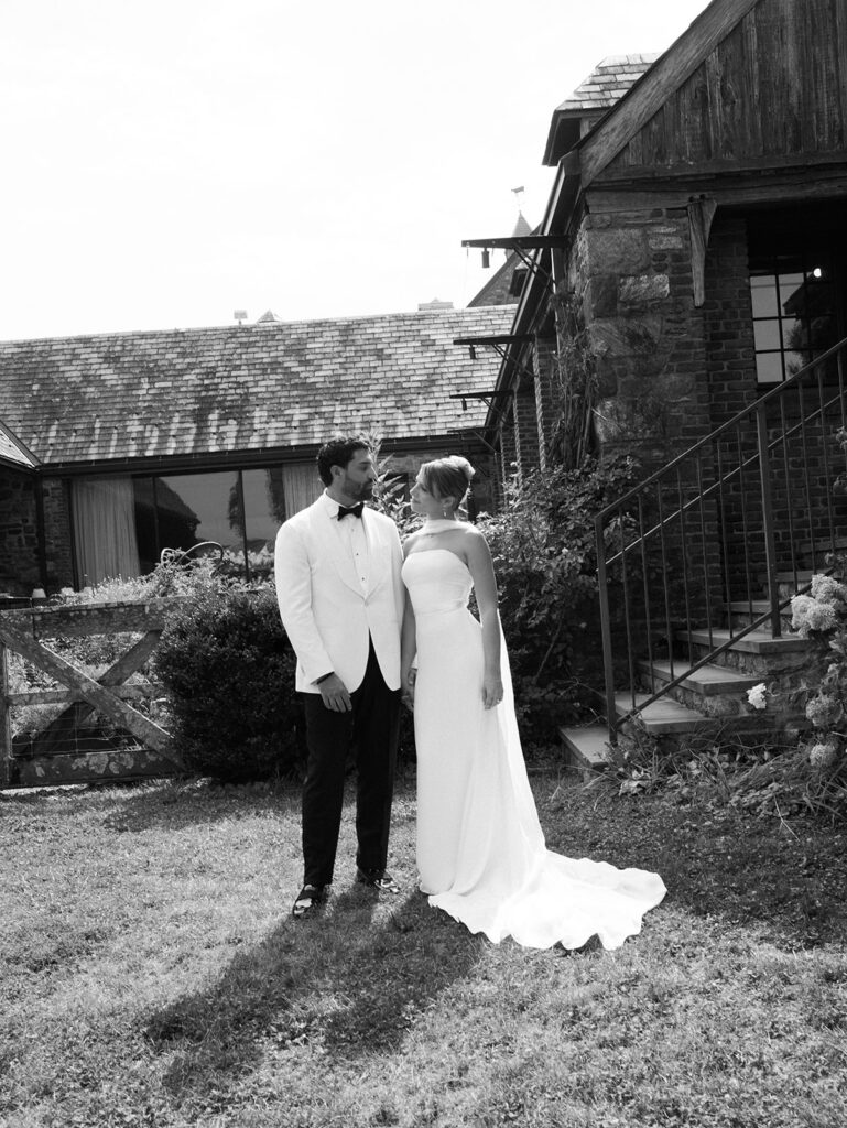The bride and groom share a candid moment in black and white.