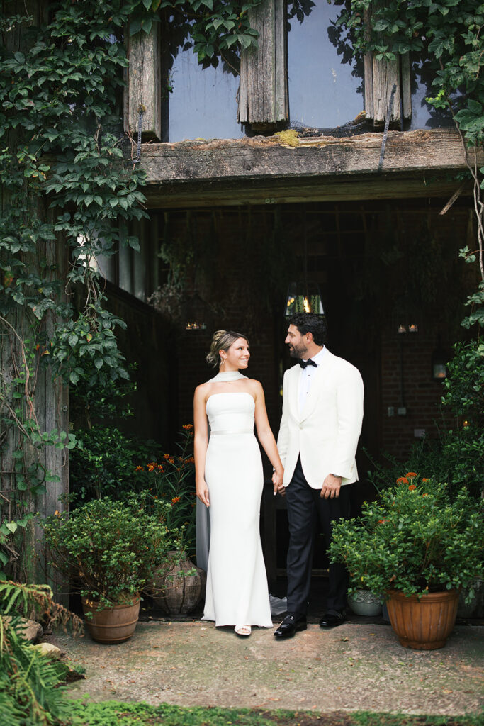 The bride and groom standing in front of the barns.