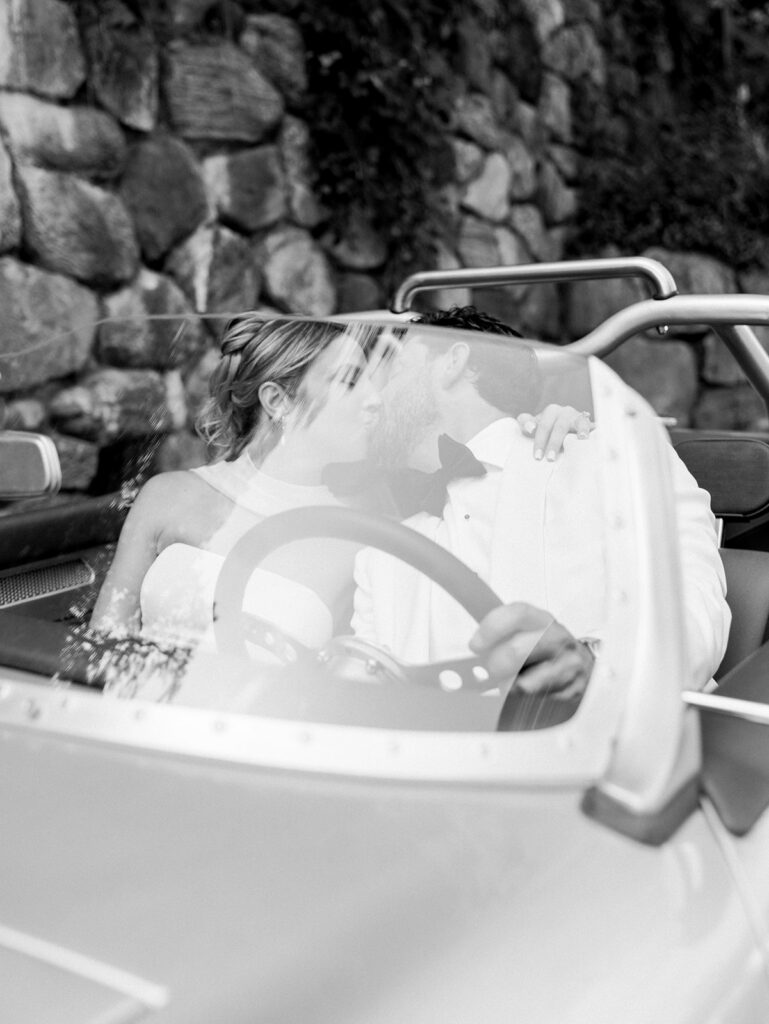 The bride and groom kissing in the car.
