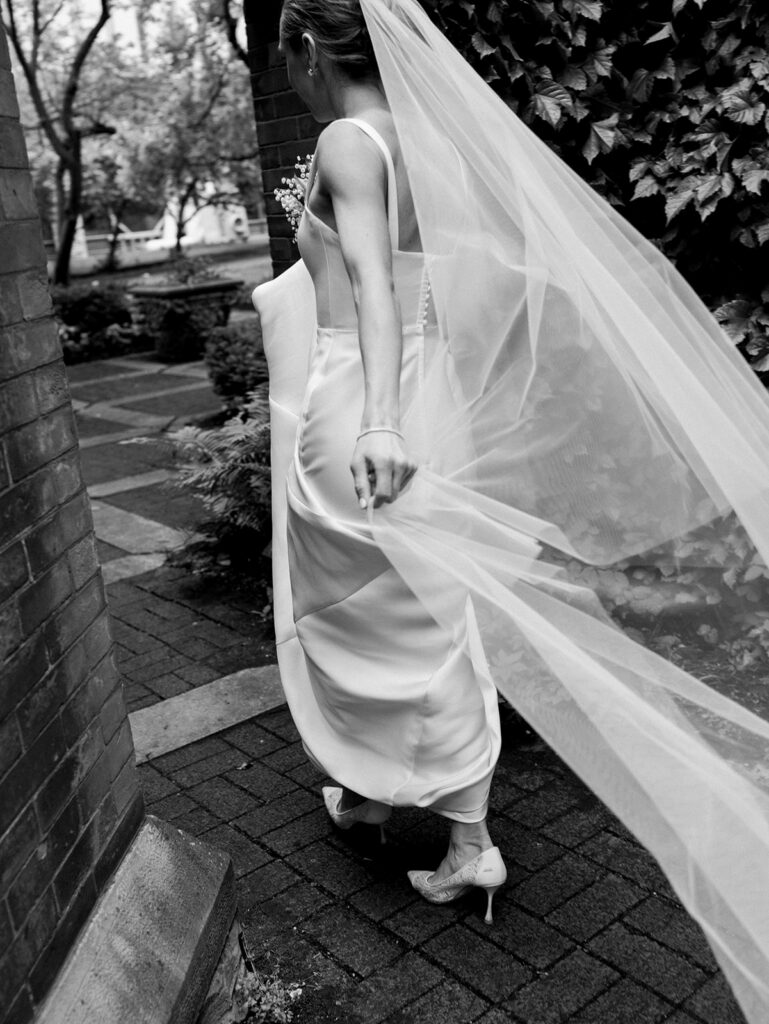 Bride walking toward the portrait location in a candid moment holding her veil.