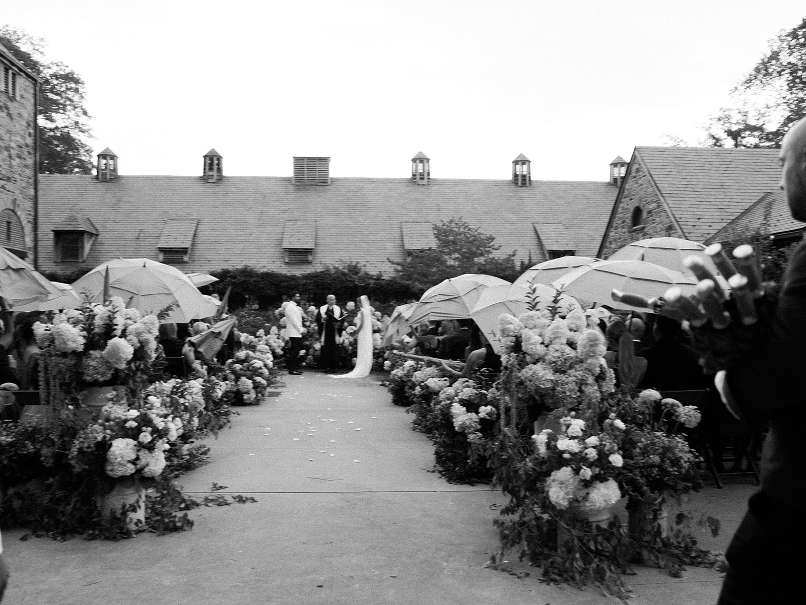 A documentary image of a wedding during which it started to rain and guests are gathering umbrellas.